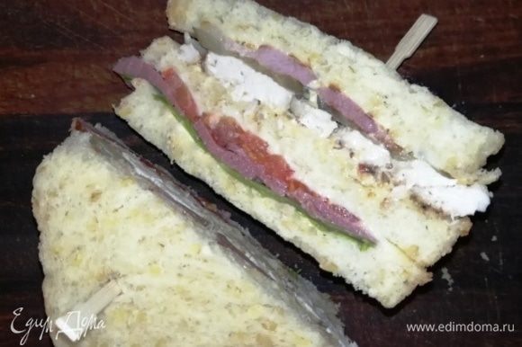 Разрезаем сэндвич, предварительно проткнув шпажками с двух сторон и подаем.