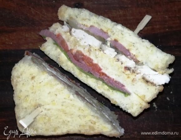 Разрезаем сэндвич, предварительно проткнув шпажками с двух сторон и подаем. 