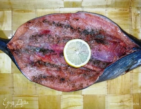 Разверните рыбу лодочкой, посолите, поперчите, полейте лимоном.