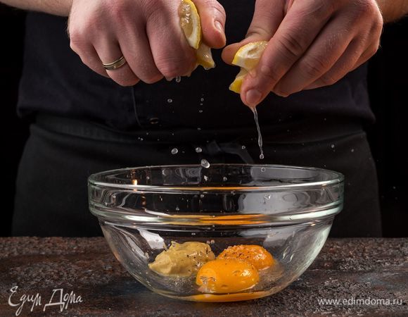 Отварите 5 небольших картофелин, яйца. Тем временем приготовьте домашний майонез. Соедините в миске 2 желтка, горчицу. Из лимона выжмите сок. Посолите, поперчите и разотрите венчиком.