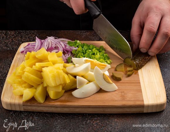 Приступим к приготовлению салата. Вареный картофель очистите и нарежьте ломтиками. Также нарежьте кубиками яйца, маринованные огурцы. Зеленый и репчатый лук мелко нарежьте, с кукурузы слейте жидкость.