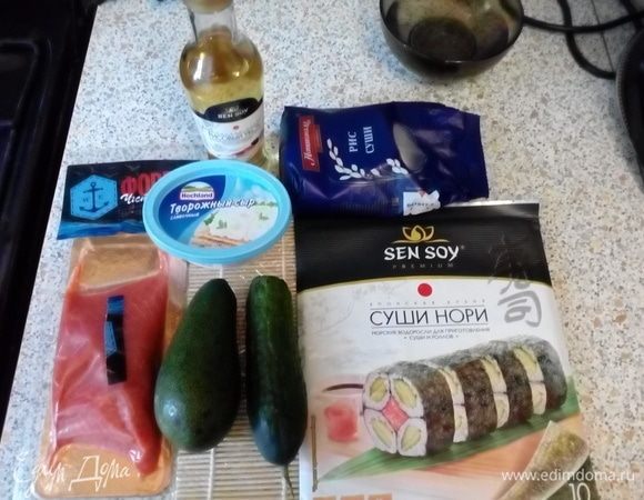 Подготовить ингредиенты. Сварить рис (1 к 2), добавить 2 ст. л. рисового уксуса и настоять под крышкой ~15 минут. Нарезать рыбу, огурец и авокад. 