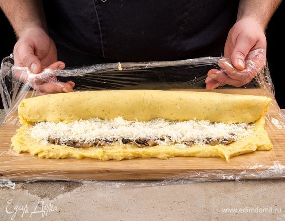 С помощью пленки сверните рулет. Защипните края. Выложите рулет швом вниз.