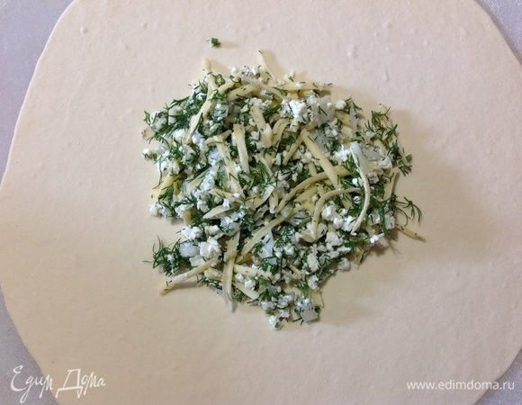 Берем кусочек теста, обваливаем его в щепотке муки и раскатываем его в лепешку тонко, но не так, чтобы светилось.
Посередине выкладываем начинку, где-то 2 ст. л. и собираем края теста по кругу волнистыми защипали, собрали и закрепляем в центре.