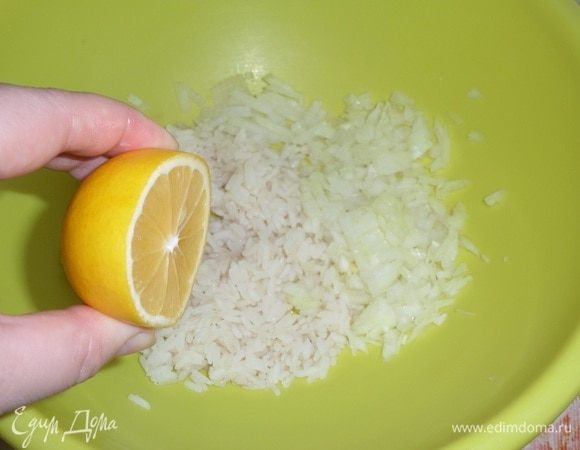 Остуженный рис выкладываем в чашку. Добавляем мелко нарезанный лук и сок половины лимона.