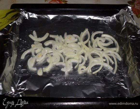 На противень расстилаем фольгу. Сбрызгиваем маслом. Выкладываем нарезанный полукольцами лук.