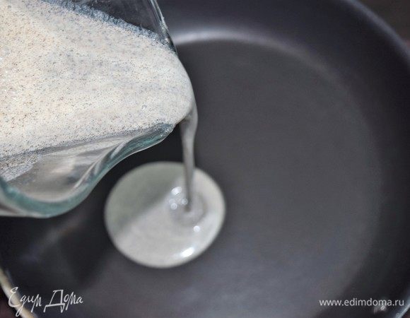 Достаньте тесто для блинов из холодильника. Добавьте полстакана горячей воды и перемешайте тесто. Должно получиться жидкое тесто, которое легко льется. Пожарьте блины. В зависимости от размера сковородки получается 8–10 блинов.