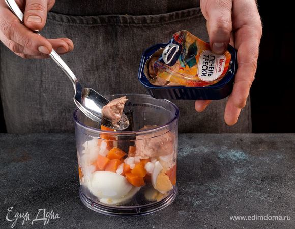 С печени трески ТМ «Магуро» слейте жидкость. Сложите в чашу блендера печень трески, яйца, морковь, репчатый лук. Все измельчите до однородного состояния.