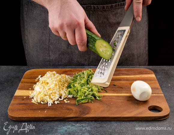 Отварите куриные яйца, очистите и натрите на терке. Натрите на терке огурец вместе с кожурой.