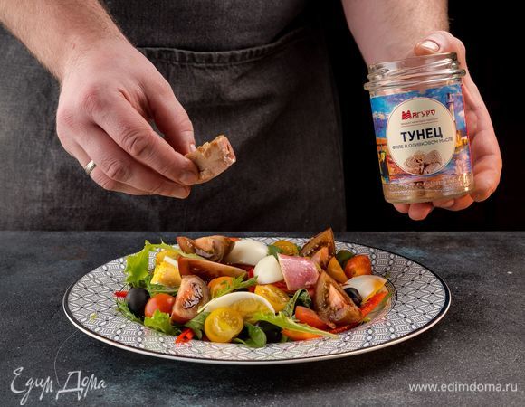 На сервировочную тарелку выложите листья салата, на них выложите овощи, яйца и маслины. Добавьте тунца в масле в салат. 