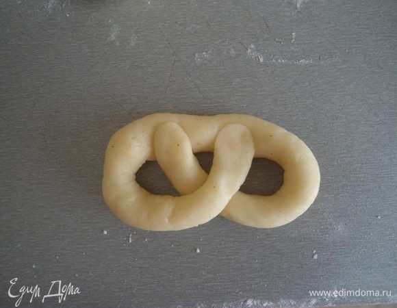 Свернуть кренделем. Дополнительно много муки не используйте, иначе посыпка потом плохо прилипнет.