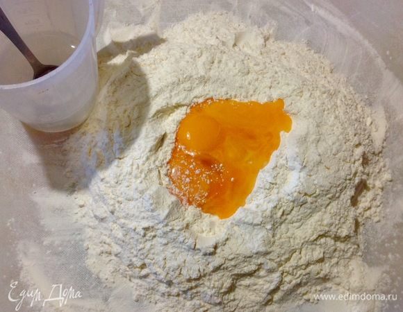 Для начала о количестве ингредиентов:  я указала количество ингредиентов, которые у меня ушли на эту лапшу, но есть НО, количество может варьироваться, так как у нас с вами могут быть разные по размеру желтки, разная мука, поэтому плюс минус в ингредиентах вы должны учитывать. Тесто надо чувствовать, сильно крошится — добавьте чуть порциями воды, слишком липкое — добавьте порциями муки.
Итак: просеиваем на рабочую доску муку, делаем в ней отверстие по середине,
выливаем туда желтки, пальцами вмешиваем их в муку.