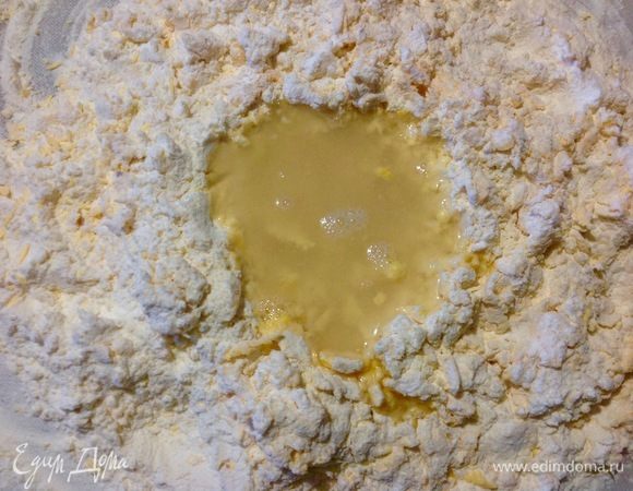 Сначала я налила в мерный стаканчик 80 мл воды, развела в ней 1 ч. л. соли и вливаем эту воду в лунку из муки и желтков, и замешиваем пальцами не всю муку, а ту часть которая ближе находится к лунке с водой.
На этом моменте смотрим нужна ли еще вода, у меня была такая необходимость я добавила еще 30-40 мл воды и стала замешивать уже всю муку, что просеяна на рабочей доске.
Комок теста получается тугой и твердый, здесь понадобится сила в руках, надо месить этот упругий комок теста минут 10, радостно улыбаясь. :)