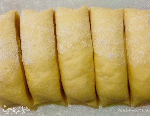 30 минут прошли, делим колбаску из теста на пропорциональные кусочки, один берем для раскатки, а остальные кладем обратно в пленку и заматываем их, так каждый раз когда забираем следующий кусочек теста, это делается для того чтобы тесто не обсыхало пока мы занимаемся раскаткой.