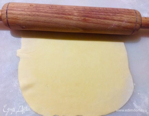 Кусочек теста раскатываем тонко, раскатали, присыпаем мукой и размазываем муку по раскатанному пласту теста.