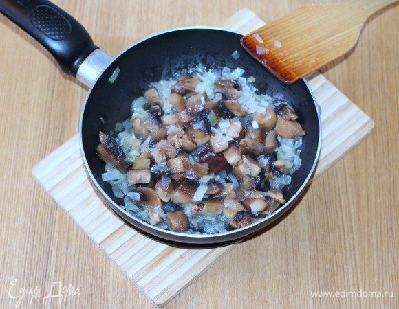 Добавляем порезанные дольками шампиньоны, сливочное масло, солим, перчим и жарим до готовности грибов.
