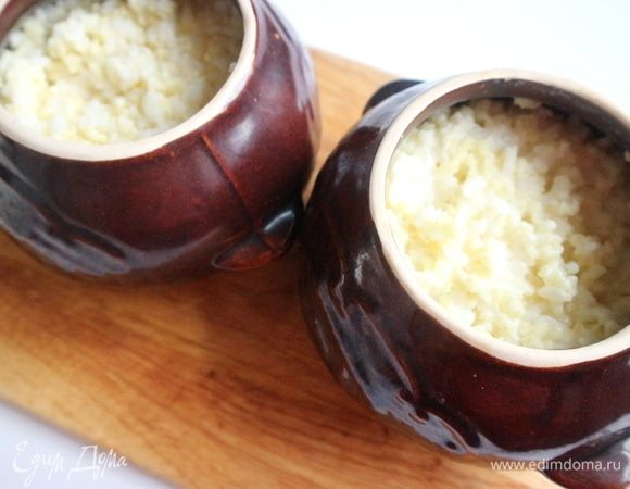 Поместить горшочки, накрыв крышками, в духовку на 60 минут. Через минут 25–30 после начала приготовления вынуть горшочки, перемешать содержимое ложкой. Вернуть горшочки в духовку. За 15–20 минут до окончания приготовления крышки снять с горшочков, чтобы молоко «не убежало» в духовку.  