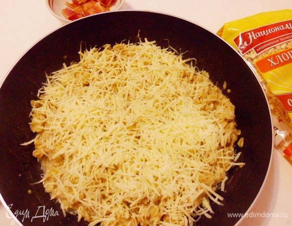 За минуту до готовности овсяных хлопьев добавить в сковороду тертый сыр.