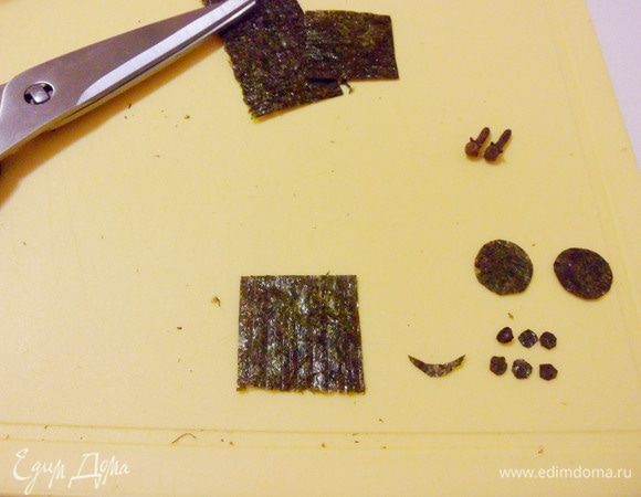 Из листа водорослей нори ножницами вырезать «улыбку» медвежонка и кружочки разного размера для лапок «ножек».