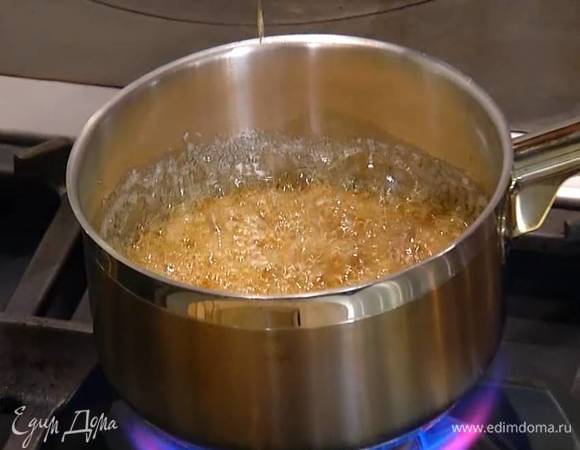Сахар всыпать в небольшую кастрюлю, влить 60 мл воды, поместить на огонь и варить 5‒7 минут до темного золотистого цвета, затем снять кастрюлю с огня и, непрерывно перемешивая лопаткой, тонкой струйкой влить 200 мл молока, вернуть кастрюлю на огонь и сварить карамель.
