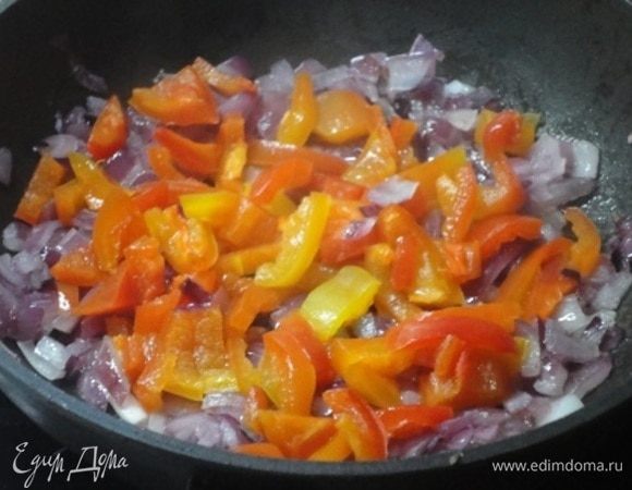 В сковороде разогреть пару столовых ложек растительного масла и обжарить мелко нарубленную луковицу (красную или белую), затем добавить кусочки болгарского перца и прожарить 2–3 минуты. Посолить щепоткой соли и приправить прованскими травами. Выложить в тарелку.