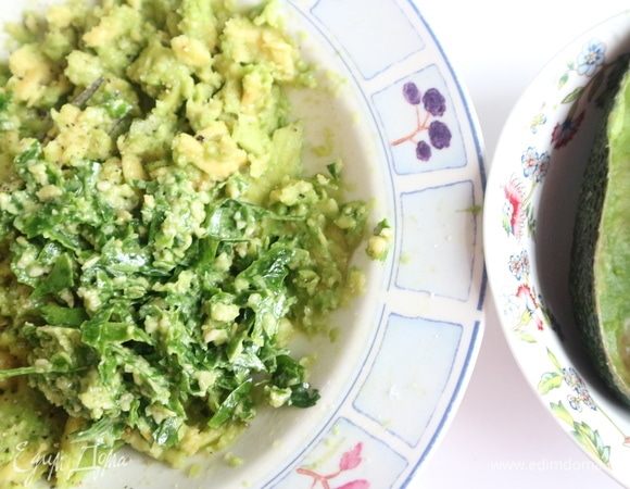 Приготовить песто из зелени. Зелень мелко нарезать, чеснок почистить, выдавить через пресс. В ступку поместить зелень, кедровые орехи, чеснок, соль, перец, оливковое масло. Растолочь. Добавить к авокадо. Перемешать.