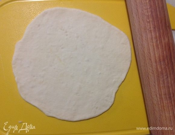 Берем одну часть теста, остальные 6 частей — обратно в миску под полотенце, чтобы не обветривались.
Тот кусочек, что взяли, снова обминаем рукой и тонко раскатываем, но не так тонко, чтобы тесто просвечивалось.