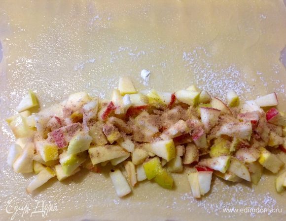 Теперь выкладываем начинку вдоль края теста, отступив немного от края.
Посыпаем 1 ч. л. сахара и 1 ч. л. корицы поверх яблок.