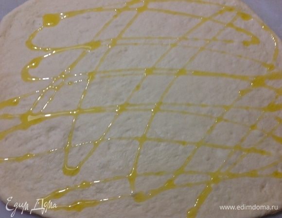 Берем одну часть и раскатываем его в пласт, вторую пока отправляем обратно в миску под полотенце, чтобы оно не обветривалось. Поверх пласта поливаем оливковым маслом.