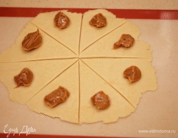 Раскатать шар в круг на силиконовом коврике (толщина теста — 2–3 мм), разделить на 8 сегментов, на каждый выложить по 1 ч. л. вареной сгущенки.