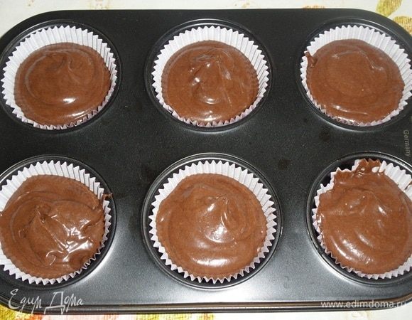 Выкладываем приготовленное тесто в форму для кексов, вложив бумажные капсулы. Наполняем капсулы на 2/3 объема.