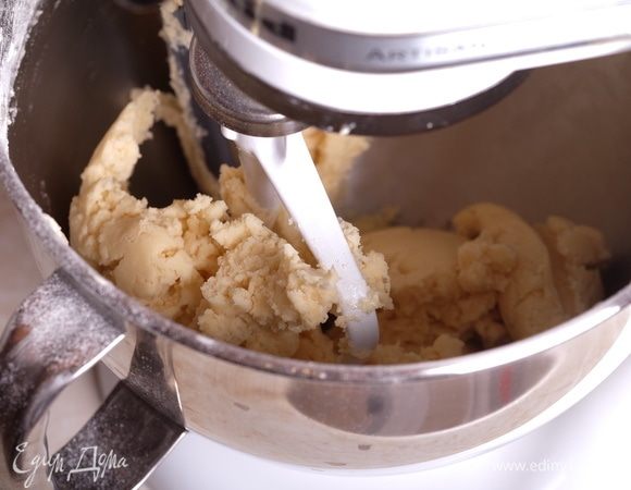 В полученное тесто просеять муку, смешанную с содой, замесить мягкое тесто. Долго мешать нельзя — как только тесто собралось в ком — прекращать перемешивание. Если долго мешать, песочное тесто при выпечке становится очень твердое и не рассыпчатое.