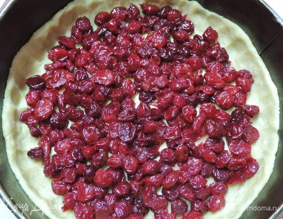 Тесто распределяем по форме диаметром 22–23 см, выстеленной пергаментом, формируя высокие бортики. Выкладываем слой вишен.