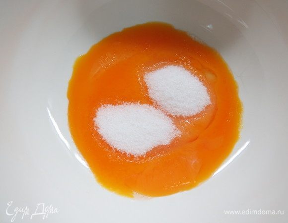 Тем временем венчиком смешать желтки со второй половиной сахара. 