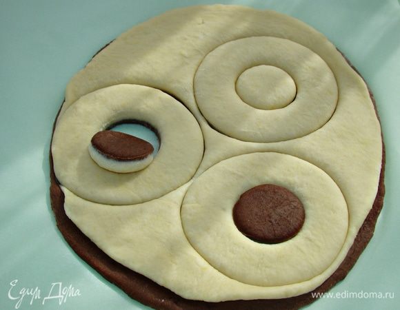 Раскатанные части теста уложить друг на друга и вырезать или выдавить круги широкой чашкой или стаканом. Серединку выдавить рюмкой и перевернуть вверх дном. Готовые булочки уложить на противень, застеленный пекарской бумагой. Булочки смазать взбитым яйцом, оставить минут на 20 для подъема и выпечь в разогретой до 180°С духовке минут 30. 