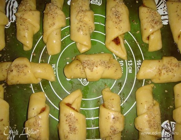 Через 1,5 часа рогалики увеличились в объеме. Смазать рогалики белком взбитым с водой. Сверху посыпать рублеными орешками и поставить в разогретую до 170°С духовку на 30–35 минут. 