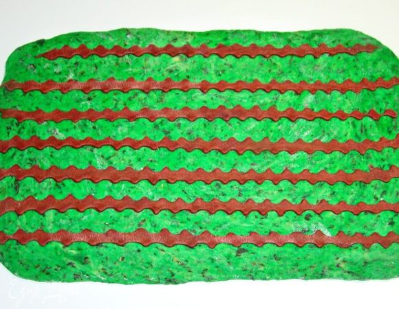 Раскатать шпинатное тесто в прямоугольник и сверху уложить коричневые полоски теста, слегка придавить скалкой. 