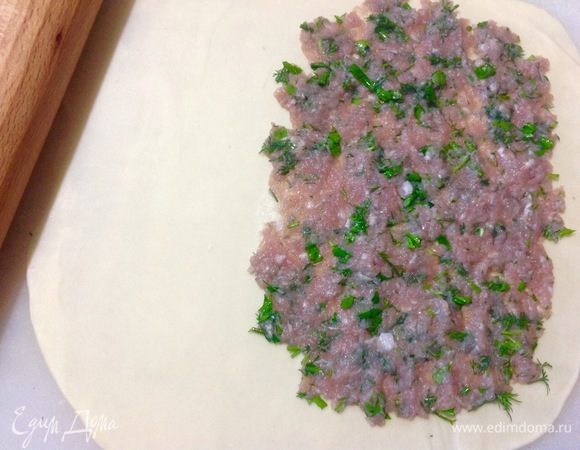 На одну половину теста выкладываю столовую ложку фарша, и пальцами его надо распластать тонко по этой половине теста, отступив от края пласта.