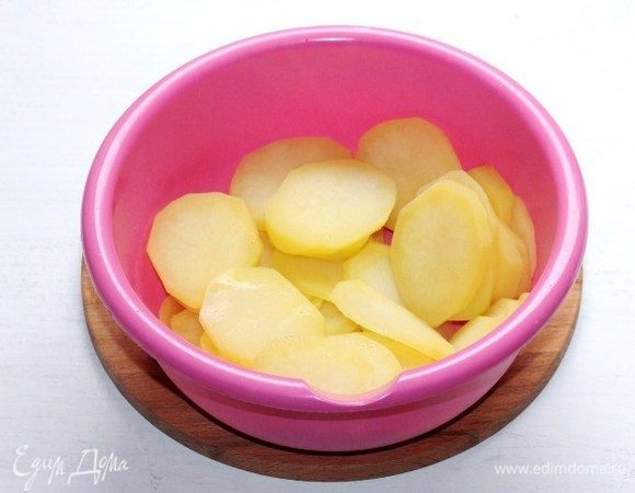 Очищенный картофель нарезаем тонкими кружочками (~0,5 см) и отвариваем в подсоленной воде до полуготовности. Затем отвар сливаем, картофель выкладываем в миску.
