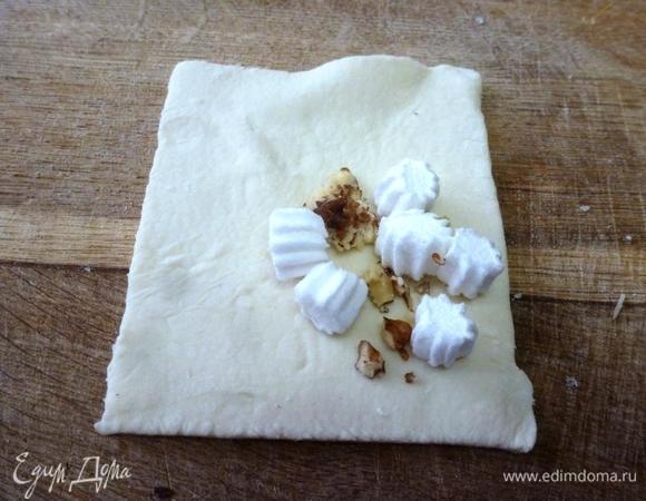 Маршмеллоу нарезать на кусочки помельче, орехи измельчить. На одну сторону каждого квадратика кладем несколько кусочков маршмеллоу и грецких орехов.