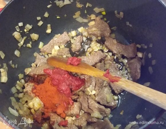Добавить порошок сладкой красной паприки и томатную пасту, коротко обжарить.  