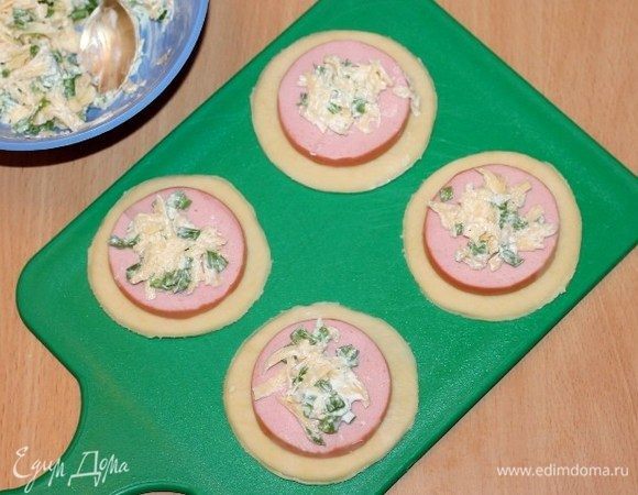 Берем один кружок теста, кладем на серединку кружок колбасы, затем 1 ч. л. начинки.
