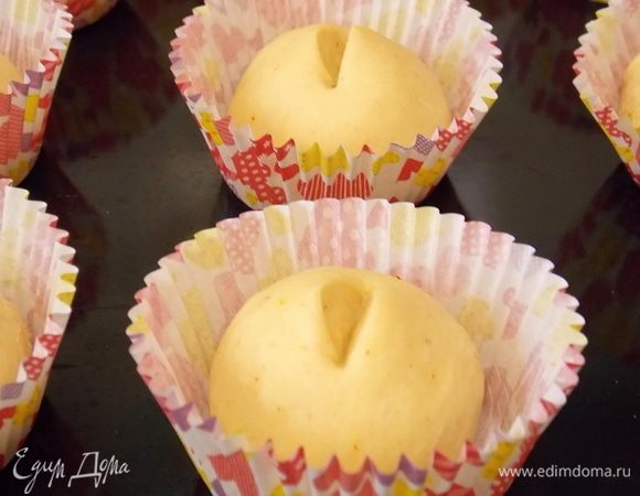 Разделить подошедшее тесто на 16 одинаковых частей и скатать их в шарики.  Уложить каждый в бумажную форму для кексов. Сделать разрез при помощи ножниц.