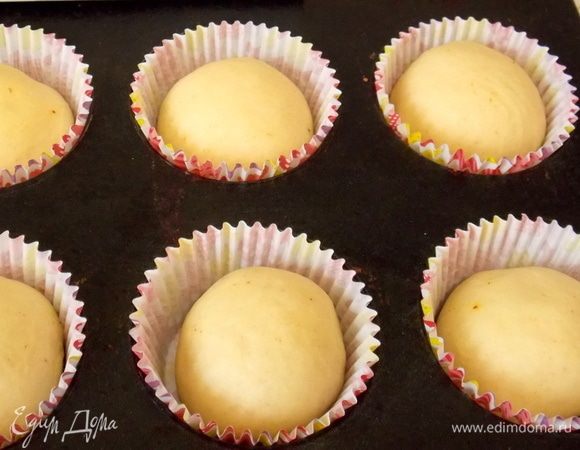 Подошедшее тесто разделить на 15–16 частей. Раскатать не очень сильно, распределить шоколадную начинку, защипать края и скатать в шарики. Разложить их в бумажные формочки для кексов. По желанию смазать верх сладким чаем.