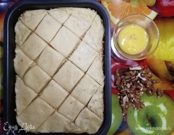 Наметьте  тесто на  порционные заготовки. Яйцо взбейте. Грецкие орехи разрежьте на 2 части. 