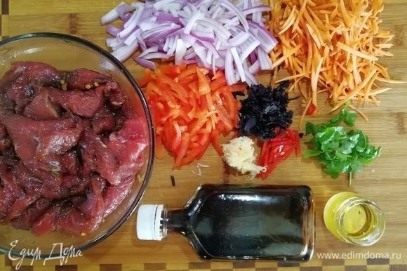 Подготовьте говядину, замаринованную в чесноке, перце, соли и оливковом масле. Морковь натрите, болгарский перец нарежьте тонкой соломкой, лук полукольцами, чили соломкой, чеснок натрите, базилик порежьте, петрушку порвите.