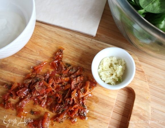 Духовку разогреть до 180°С. Очистить чеснок, выдавить через пресс. Вяленые в масле томаты нарезать на кусочки.