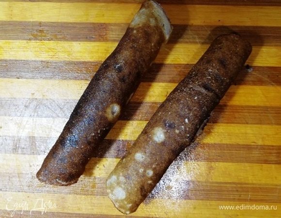 Сверните блинчики трубочкой и разрежьте пополам.