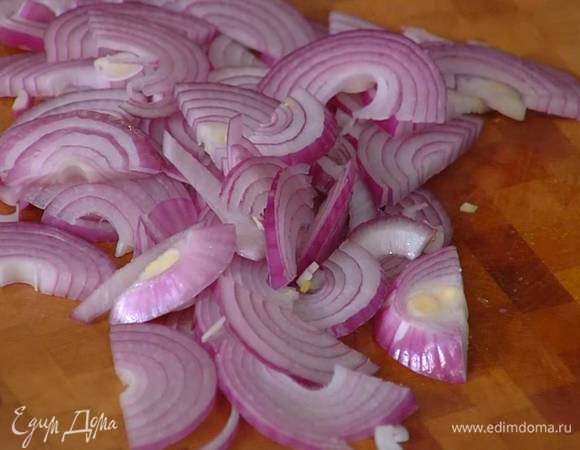 Красный лук почистить, нарезать тонкими полукольцами и выложить в глубокую тяжелую сковороду.
