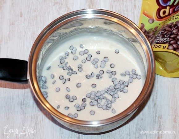 В охлажденный крем добавляем 2 ст. л. сметаны с горкой, перемешиваем. Затем шоколадные дропсы 2–3 ст. л. или небольшие кусочки шоколада, перемешиваем. 
